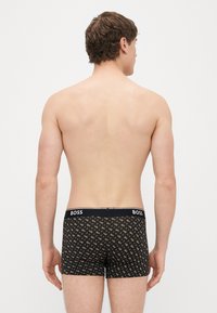 Μαύρα ανδρικά μποξ�εράκια με γεωμετρικό μοτίβο, με λογότυπο στη μέση. Ομαλή υφή και εφαρμοστό σχέδιο.