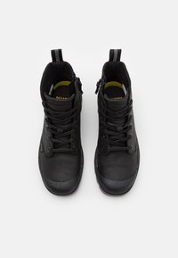 Botas de tobillo negras de cuero texturizado, con puntera redonda, cordones en la parte delantera y cierre de cremallera en el lado. Suela de goma negra.