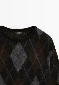 Maglione con motivo argyle in bianco e nero, realizzato in un materiale morbido e peloso. Presenta un colletto rotondo e un'etichetta all'interno del colletto.