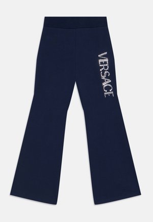 Pantalones acampanados de color azul marino, confeccionados en una tela suave, con un logo de "VERSACE" adornado con rhinestones en la pierna izquierda.