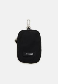 Schwarze Nylon-Tasche mit einem silbernen Clip, Reißverschluss und einem rechteckigen Etikett mit der Aufschrift "Desigual" in weißem Text. Kompaktes und einfaches Design.
