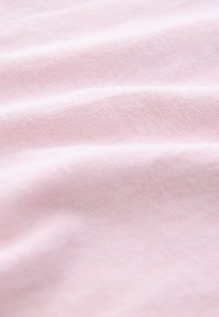 Svijetloružičasti pamučni materijal s mekanom teksturom, s blagim varijacijama u nijansi i nježnim naborima koji ukazuju na sposobnost pada tkanine.