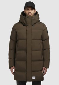 Brauner Puffercoat mit einem Reißverschluss vorne, verstellbarem Kapuzen und großen gesteppte Abschnitten. Mit seitlichen Taschen und einem Markenpatch am Saum.