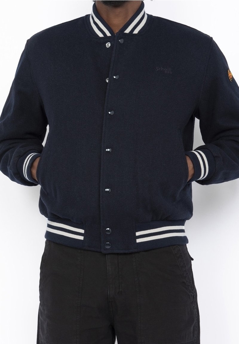 Giacca varsity in misto lana blu navy con collo e polsini a costine bianchi a righe, dotata di bottoni a pressione e tasche laterali.