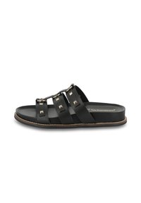 Black leather slide sandal featuring three wide straps, square studs, and a circular buckle. Flat sole with light brown trim.