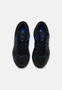 Mustat urheilukengät sinisillä yksityiskohdilla, verkkomateriaalia ja synteettistä yläosaa, teksturoitu pohja, jossa on kolme raitaa ja emblemillä varustettu kieli.
