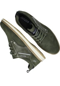 Zelené perforované kožené boty s béžovou gumovou podešví, šněrovací design a bílé švy. Obsahuje štítek na jazyku.