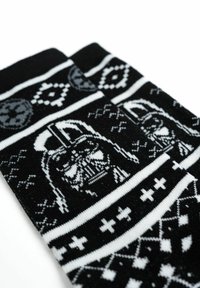 Calze a righe in bianco e nero con un design grafico di una figura con casco, accompagnata da forme geometriche e strisce. Morbido tessuto lavorato a maglia.