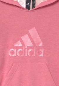 Felpa Adidas rosa con tasca frontale e grande logo Adidas in rilievo sul petto, con le etichette visibili all'interno del colletto.