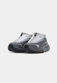 Pantofi sport gri, confecționați dintr-un amestec de plasă și materiale sintetice, având un închidere cu fermoar și o talpă din cauciuc texturat cu detalii Vibram.