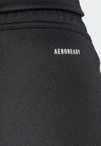 Black athletic pants made from textured fabric, featuring a fitted design and a small white "AEROREADY" logo on the back.