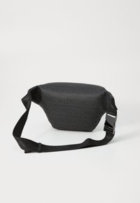 Sac bandoulière noir en nylon avec une surface texturée et un motif de logo en relief. Dispose d'une sangle ajustable robuste et d'une boucle en métal.