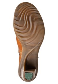Suela de zapato de cuero en tono marrón claro con un patrón texturizado ondulado, tapa de tacón de goma en verde, que presenta el logotipo de la marca y un acabado suave para mayor tracción.