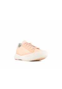 Baskets de sport rose clair avec une semelle blanche texturée, présentant une tige lisse, un bout arrondi et des motifs subtils sur les côtés.