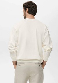 Light beige crewneck sweatshirt with long sleeves and ribbed cuffs, featuring a relaxed fit and smooth texture.