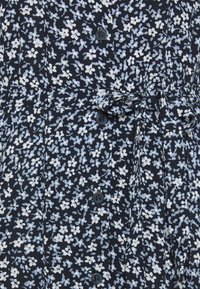 Blumenkleid aus dunkelblauem Stoff mit weißen und hellblauen Blumenmustern, einer durchgehenden Knopfleiste und einer Taillierung mit Bindeband.