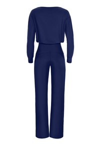 Marinblå jumpsuit med långa ärmar, hög midja och vida byxor. Slät tygkvalitet med avslappnad passform. Bakifrån syns uringning och sömmar.