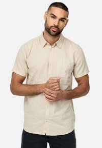Kortærmet beige skjorte med knapper, lavet af letvægtsstof, med en brystlomme og en klassisk krave. Subtil tekstur med en afslappet pasform.