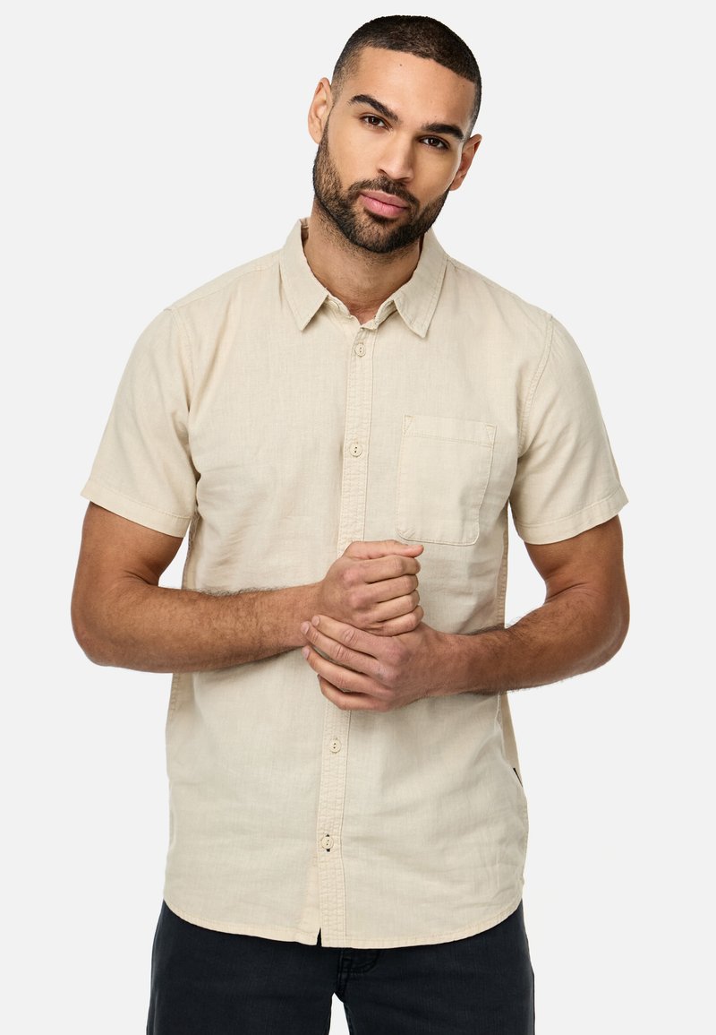 Kortærmet beige skjorte med knapper, lavet af letvægtsstof, med en brystlomme og en klassisk krave. Subtil tekstur med en afslappet pasform.