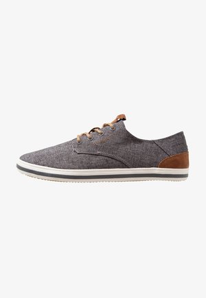 Chaussure décontractée à lacets en tissu gris avec des accents marron clair sur le talon et les lacets, semelle blanche avec bande grise, et design profil bas.