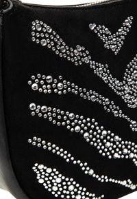 Sort ruskind clutch taske med et struktureret design af varierede størrelser klare rhinsten arrangeret i bølgemønstre på overfladen.