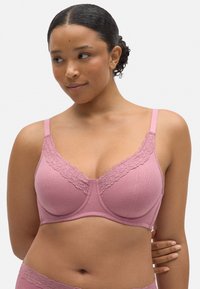 Sostén rosa de canalé con encaje en los bordes y soporte con aros. Las tirantes ajustables y una textura suave realzan el diseño.