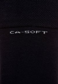 Marineblaue Socken aus einem weichen, strukturierten Material mit geripptem Design; zeigen weißen Text mit der Aufschrift "C-SOFT" in der Nähe des Bündchens.