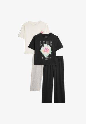 Twee t-shirts in beige en zwart, met bloemenontwerpen en bedrukte tekst, gecombineerd met grijs en zwart wijde broek. Katoenen materiaal.