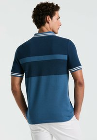Navy blue polo shirt with textured fabric, featuring horizontal stripes in lighter blue. White accents on the collar and sleeves.