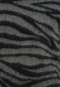 Πλεκτό πουλόβερ με γκρι βάση και μαύρο σχέδιο σε ριγέ μοτίβο ζέβρας. Μαλακή υφή με ορατή αίσθηση χνουδιού. Τονισμένες οριζόντιες γραμμές.
