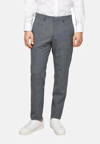Grijs geruite broek met een tailored fit, riemlussen en een platte voorkant, gecombineerd met witte sneakers tegen een effen achtergrond.