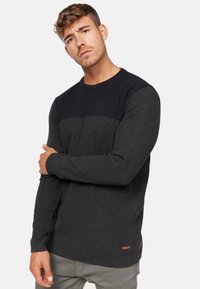 Langærmet sweater i sort og gr�å med tekstureret strikdesign. Indeholder et lille brandmærke ved sømmet.
