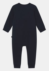 Granatowy, długosleeveowy kombinezon wykonany z miękkiego materiału, z prążkowanymi mankietami i okrągłym dekoltem, o prostym, minimalistycznym wzorze.
