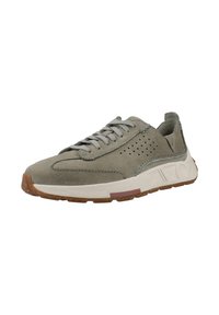 Zapatilla de ante gris claro con detalles perforados, suela de goma texturizada marrón y puntas grises. Presenta una entresuela blanca con un acento de color.