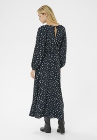 Navy long-sleeve dress with a floral pattern, featuring a keyhole back, fitted waist, and flowing skirt. Paired with black ankle boots.