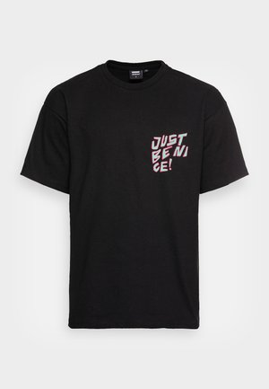 Sort bomulds t-shirt med print på brystet i hvid og pink tekst, der lyder "JUST BE NICE!". Kortærmet og med standard rund hals.