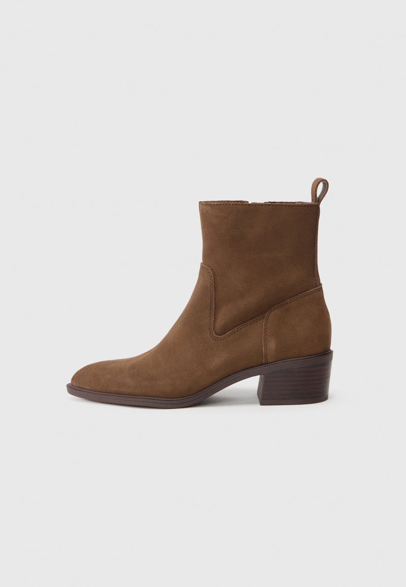 Braunes Wildleder-Ankle-Boot mit spitz zulaufender Zehenpartie, kurzem Schaft und strukturiertem, gestapeltem Absatz. Verfügt über seitliche Nähte und eine Zuglasche.