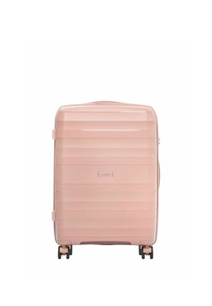 Twarda walizka w jasnoróżowym kolorze z poziomymi żeberkami, czterema czarnymi obracającymi się kółkami i górnym uchwytem.