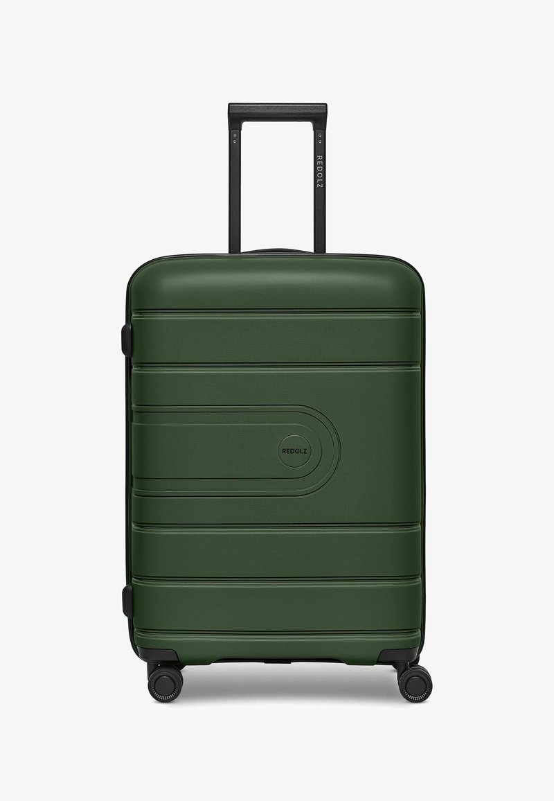 Valigia rigida verde con superficie texturizzata, scanalature orizzontali e un logo circolare. Presenta un manico estraibile nero e ruote.