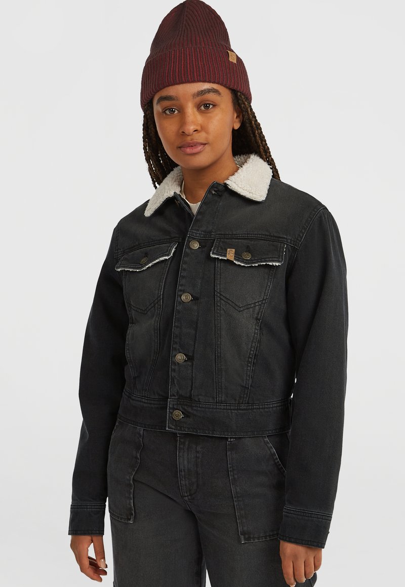 Sort denim cropped jakke med en shearling krave, frontknaplukning og to brystlommer. Båret med en mørk ribbet beanie.