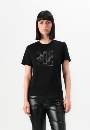 T-shirt en coton noir avec un imprime graphique de plusieurs visages en blanc et gris, à manches courtes et col rond.