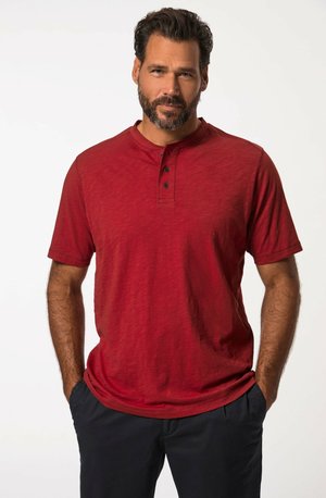Camiseta henley roja de manga corta con tapeta de tres botones. La tela parece tener textura con un sutil patrón jaspeado. Corte casual con cuello redondo.