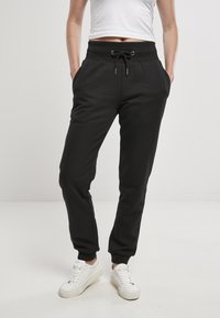 Schwarze Jogginghose mit elastischem Bund und verstellbarem Kordelzug. Hergestellt aus weichem Material, mit seitlichen Taschen und schmal zulaufenden Bündchen.