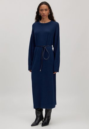 Navy blauwe lange mouwen jurk met een relaxte pasvorm, een getailleerde taille met een strikband en een zachte textuur. Draag het met kniehoge zwarte puntige laarzen.