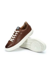 Sneaker in pelle marrone con suole e lacci in gomma bianca. Presenta una forma arrotondata, una consistenza liscia e un logo sottile sulla linguetta.