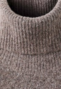 Hnědý pletený rolák se žíhanou texturou, který má silný límec a měkký, chlupatý povrch.