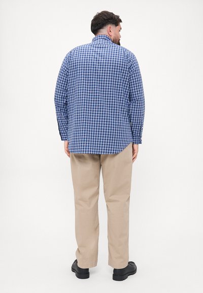 Μπλε και λευκή καρό πουκάμισο με μακριά μανίκια, κουμπωτές μανσέτες και γιακά. Συνδυάζεται με μπεζ παντελόνι και μαύρα παπούτσια.