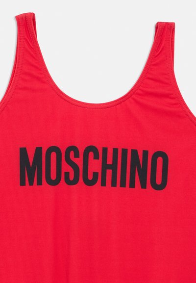 Κόκκινη φανέλα χωρίς μανίκια από μαλακό ύφασμα, με μεγάλο μαύρο λογότυπο "MOSCHINO" στο στήθος. Σχεδιασμένη με φαρδιές τιράντες και στρογγυλεμένο ντεκολτέ.