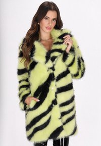 Cappotto in pelliccia sintetica di colore giallo fluorescente con motivo a righe nere, caratterizzato da un ampio colletto, due tasche frontali e chiusure a bottone.