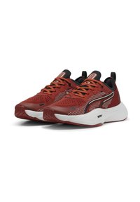 Baskets de sport rouges avec un dessus en maille, accents noirs contrastants et semelle d'amortissement blanche. Présente des détails texturés et des lacets solides.